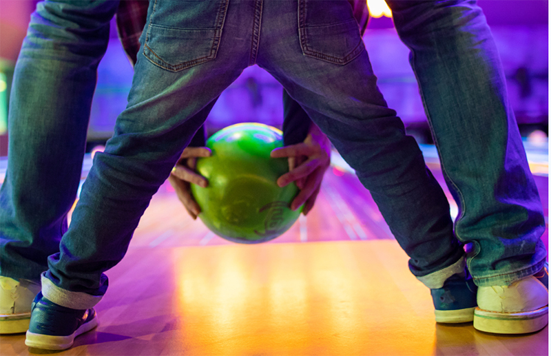 adult and child bowling together